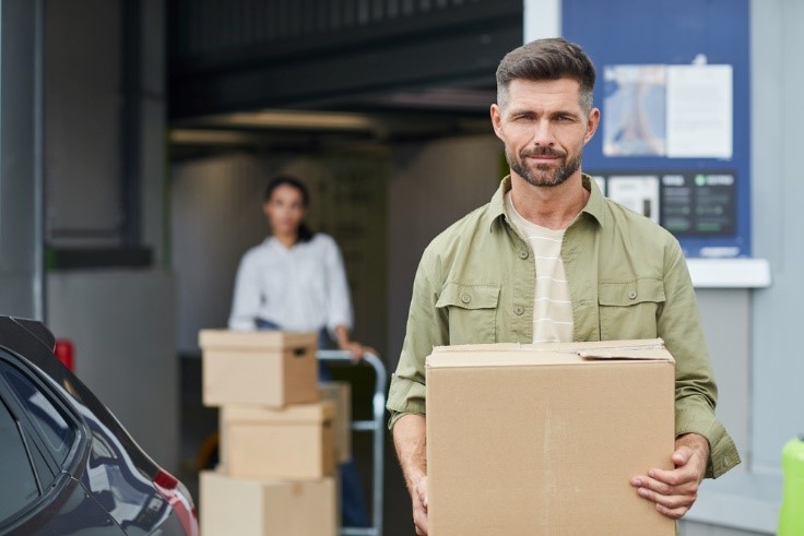 person holding a box with woman in background moving more boxes