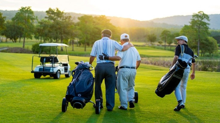 men golfing with golf bags in the green