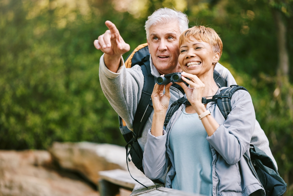 Elderly couple laughing and looking through binoculars