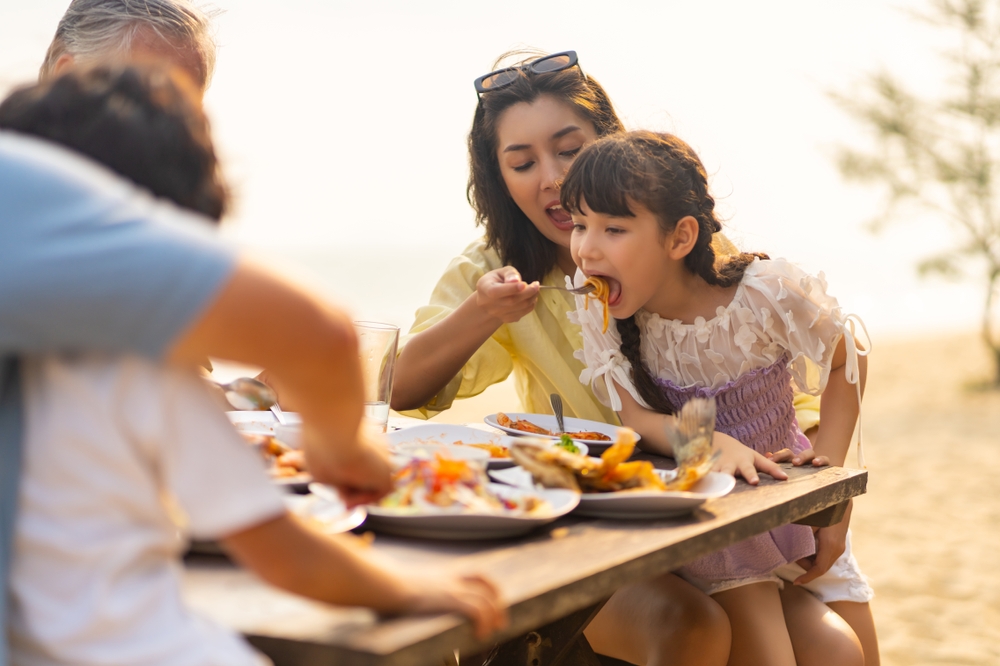 Happy family eating picnic in the summer sun