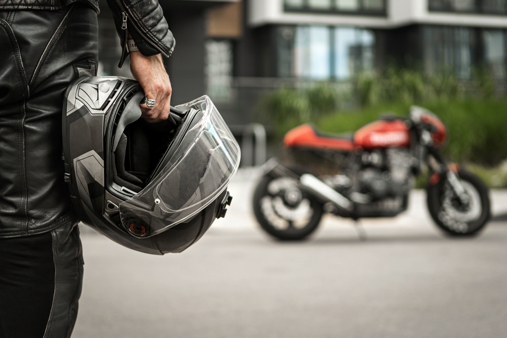 Person holding a helmet walking towards motorcycle