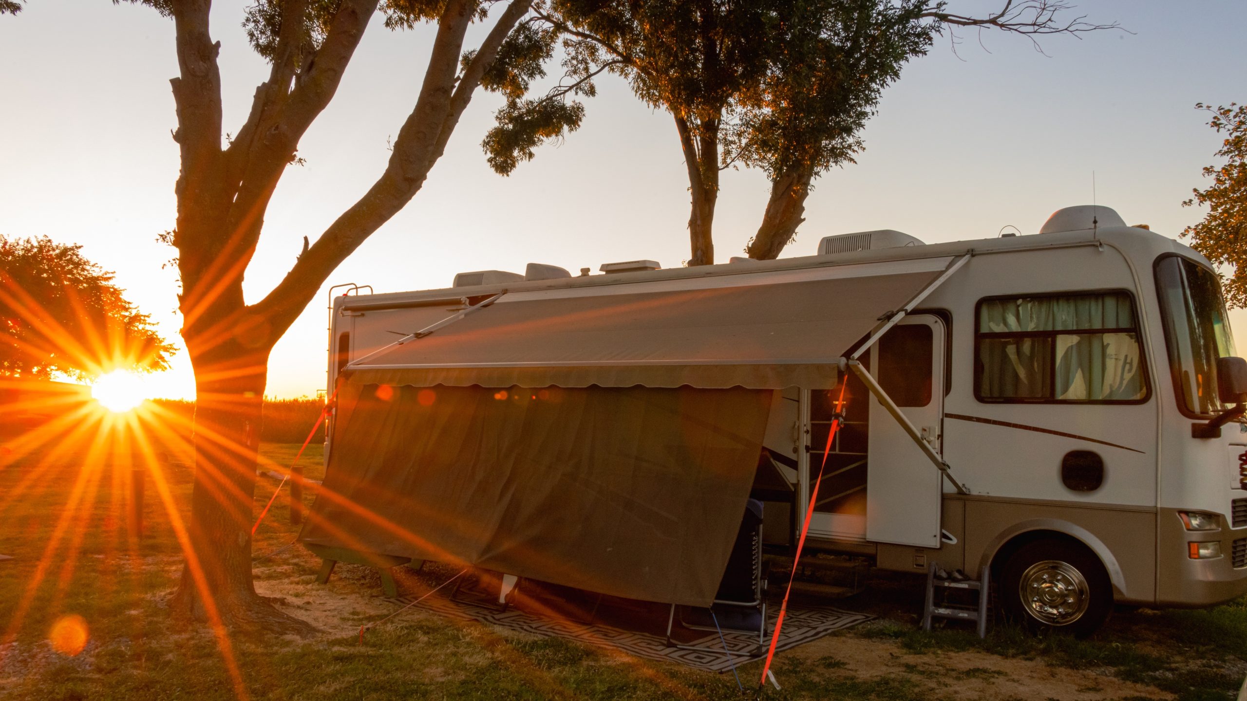 An RV camper parked in a sunny natural environment.