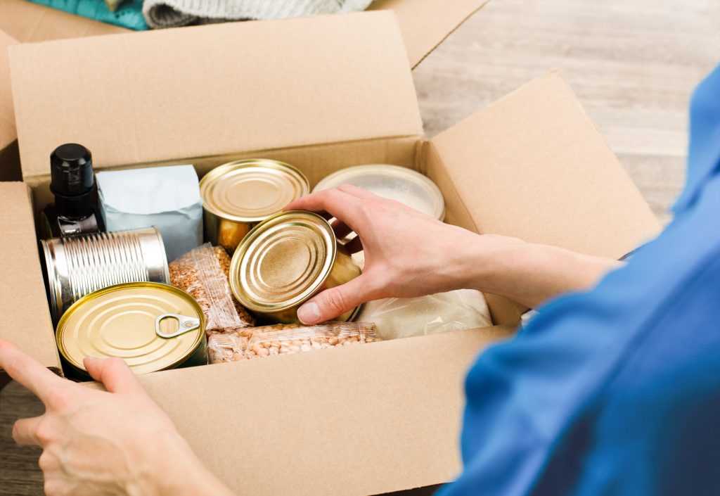 A woman puts canned food items into a care package.