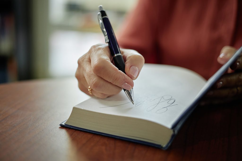 A person signing the inside cover of a book.