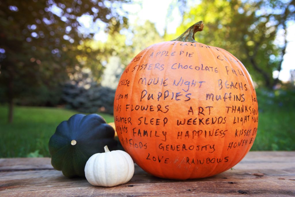 A pumpkin with words written on it, representing what people are thankful for.