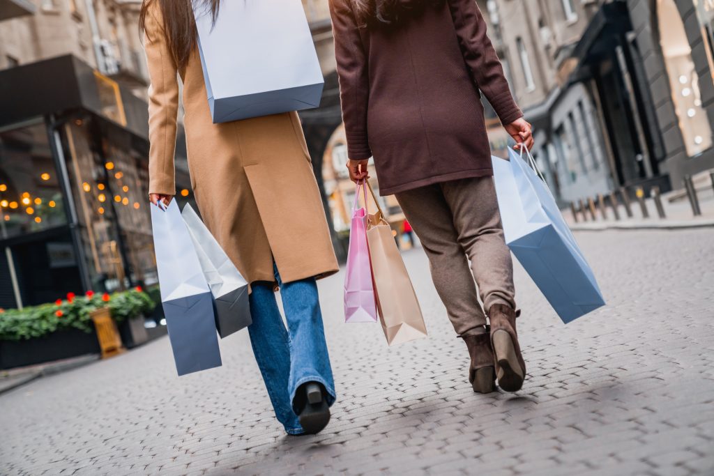 Two women walking down a city street holding multiple shopping bags.