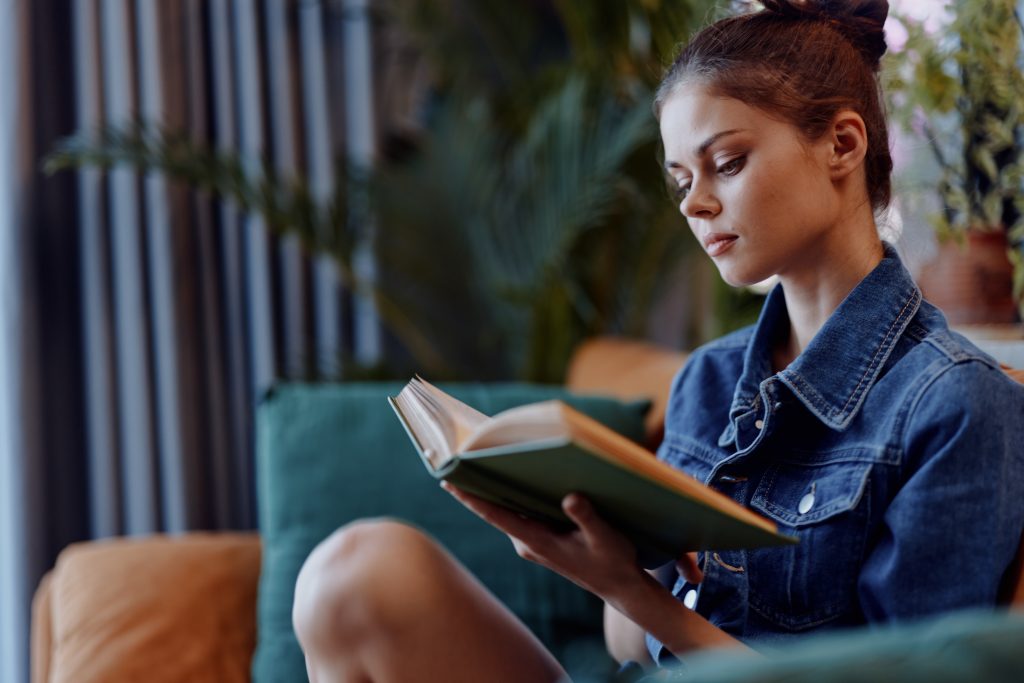 A woman reading a book on a couch.
