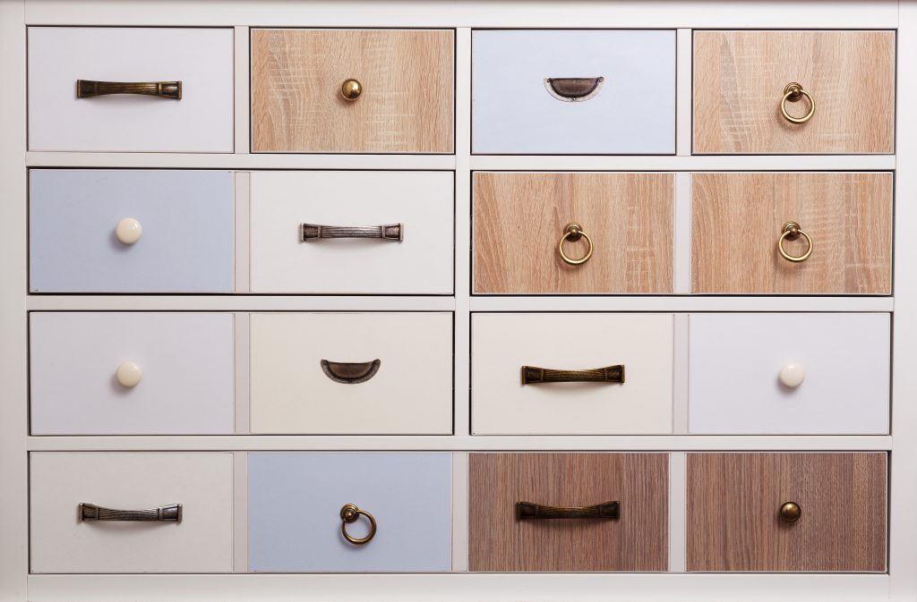Different colored drawers with different colors and styles of hardware.