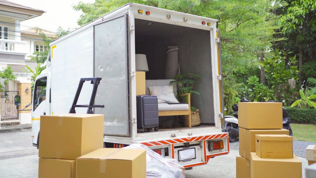 The open back of a moving truck with furniture and boxes waiting to be loaded in.