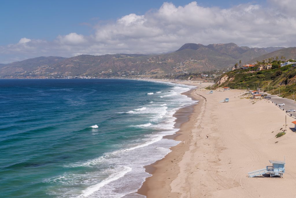 A white sand beach with blue waves crashing ashore.
