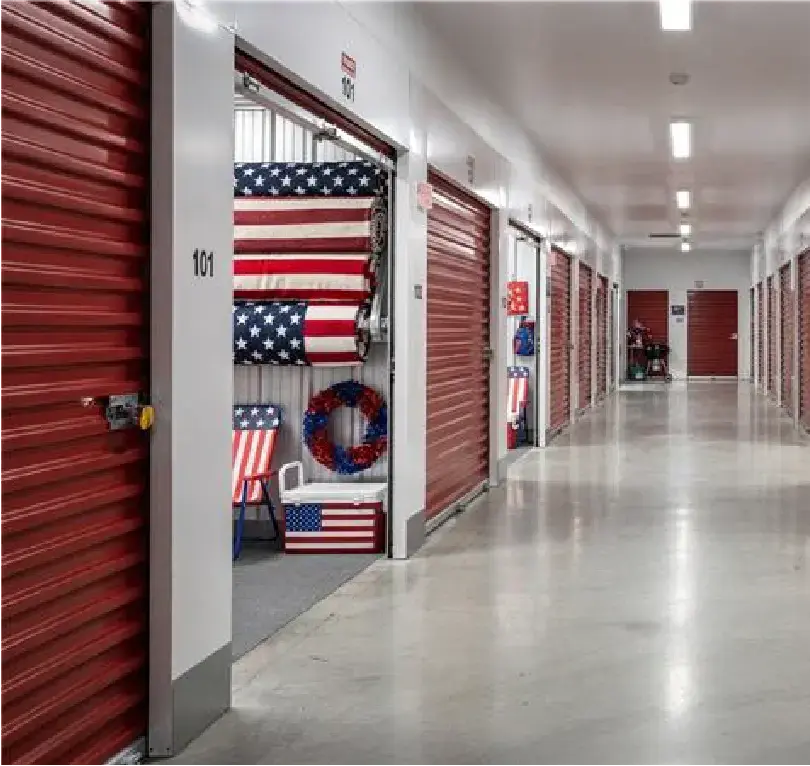 Indoor self-storage hallway with red roll-up doors.